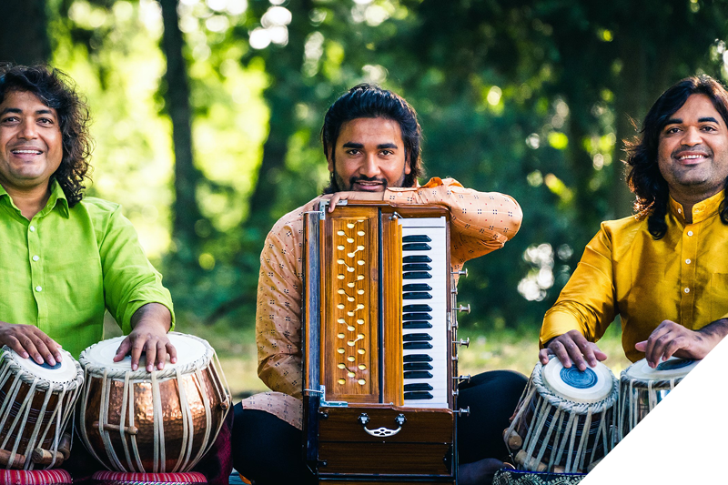 à gauche : Amrat Hussain aux tablas, au centre : Anurag Hussain tenant son harmonium, à droite : Teepu Khan aux tablas